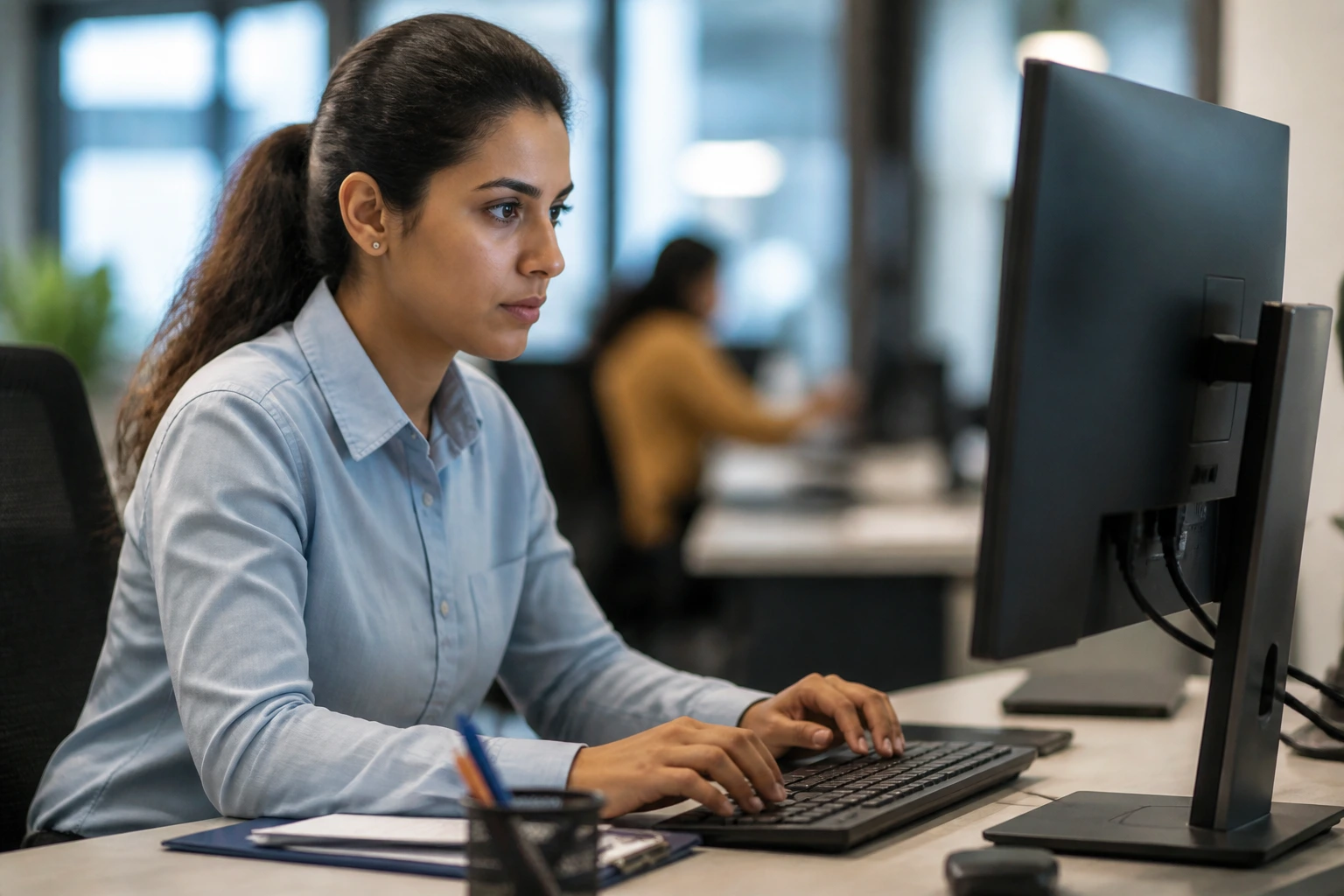 Portrait of a person at a desk representing data entry behind-the-scenes work