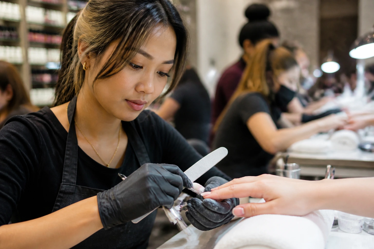 Close-up portrait of foreign nail technician at a salon station performing nails.