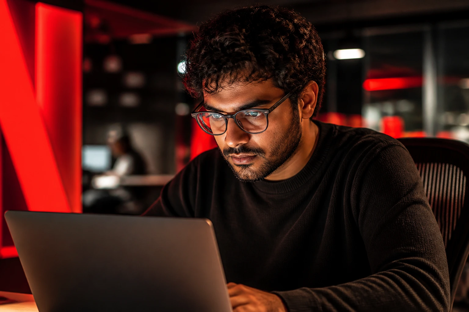 Close-up portrait of a software engineer in a Netflix-inspired office with red lighting and laptop glow