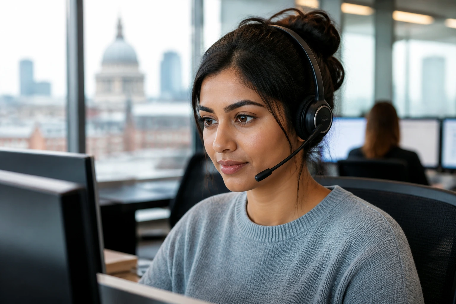 Close-up portrait of a new UK customer service agent wearing headset at a desk