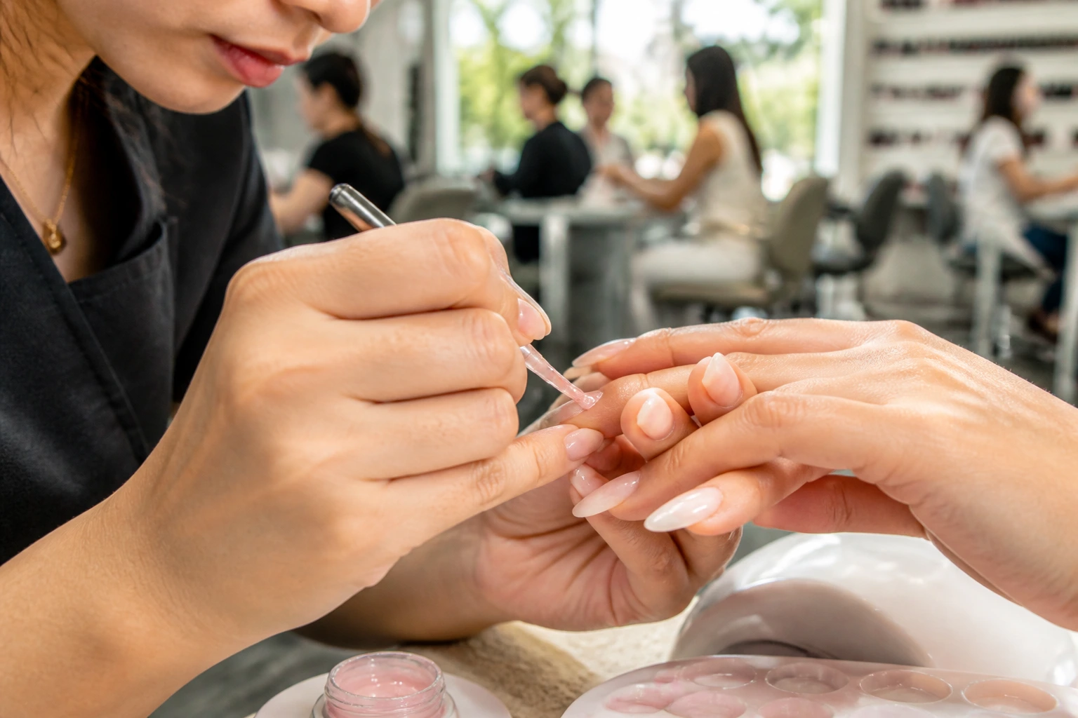Close-up of nail technician performing gel manicure in a busy Australian salon